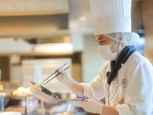 a chef in a kitchen holding a spoon and a bowl at JR Kyushu Station Hotel Kokura in Kitakyushu