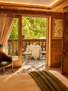 a bedroom with a bed and a balcony with a table at Gran Baita Hotel & Wellness in Courmayeur +284 photos