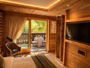 a room with a bed and a television and a table at Gran Baita Hotel & Wellness in Courmayeur