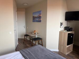 a bedroom with a bed and a table and a television at Harbour Stay Volendam in Volendam