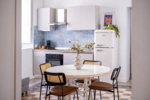a kitchen with a table with chairs and a refrigerator at BISCOTTAI Port Apartments in Trapani