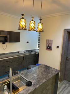 a kitchen with three lights above a sink at Sandton Luxury Apartment in Bardon Yana