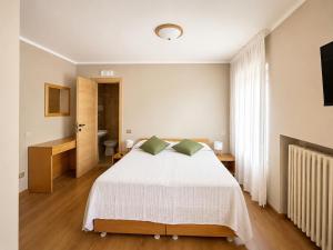 a bedroom with a white bed and a bathroom at Albergo Al Laghetto B&B in Asiago +2 photos