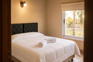 a bedroom with a white bed with a window at Olivos de Monte in San Miguel del Monte