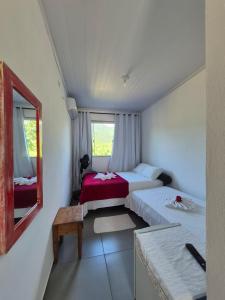 a hotel room with two beds and a mirror at Pousada Refúgio Ouro Fino - Flats & Suítes in Paraty