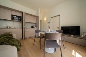 a living room with a table and chairs and a television at Flowers Liberty Suites in Brescia