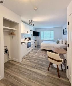 a bedroom with a bed and a table and a kitchen at Cascade Lodge Studio-steps from village in Whistler
