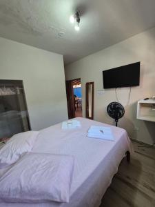 a bedroom with a white bed with a flat screen tv at Pousada Refúgio Ouro Fino - Flats & Suítes in Paraty