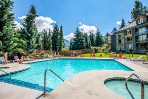 a swimming pool in a resort with people sitting around it at Cascade Lodge Studio-steps from village in Whistler