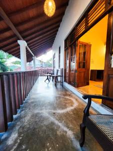 a porch of a building with benches and a table at New Moonstone Tangalle in Tangalle
