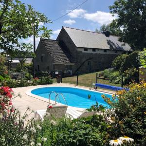 a swimming pool in front of a stone house at Walnut Tree Gîte in Boderel