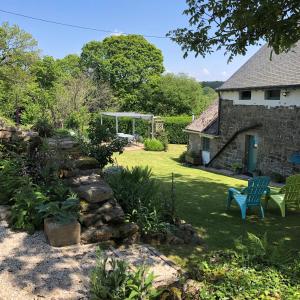 a garden with a stone wall and a blue chair at Walnut Tree Gîte in Boderel