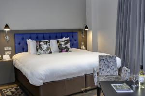a bedroom with a large bed with a blue headboard at Best Western Plus Nottingham Westminster Hotel in Nottingham