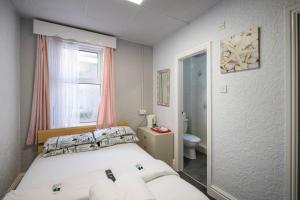a bedroom with a bed and a window and a toilet at 100 Pipers Hotel in Blackpool