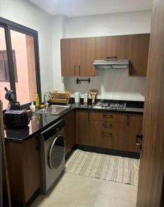 a kitchen with a stove and a sink and a dishwasher at Appartement Moderne de Standing près de route de casa in Marrakesh