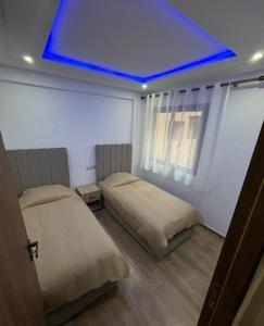 two beds in a room with a blue ceiling at Appartement Moderne de Standing près de route de casa in Marrakesh