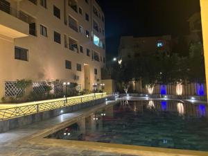 a swimming pool in front of a building at night at Appartement Moderne de Standing près de route de casa in Marrakesh