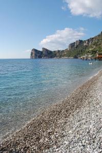a rocky beach next to the water with mountains in the background at Marina del Cantone Chalet in Nerano