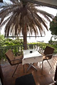a table and chairs on a balcony with a palm tree at Apartments Vila Miranda in Barbat na Rabu