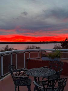 a table and chairs on a balcony with a sunset at Apart Hotel Punta Vip in Colón