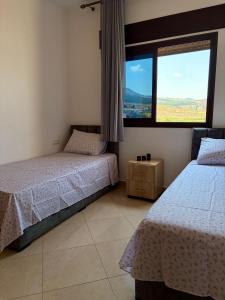 a bedroom with two beds and a large window at Paraiso Costero Azla Tetouan in Azla +79 photos