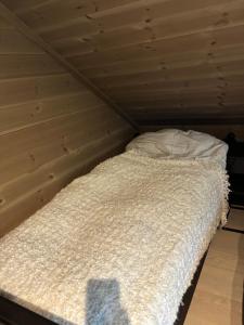 a bed with a white comforter in a room at Rom med eget bad til leie felles inngang Uten kjøkken og stue Kun overnatting in Tjørhom