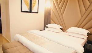 two beds with white sheets and pillows in a room at Grand East Hotel in Akwa