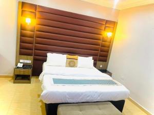 a bedroom with a large bed with a wooden headboard at Grand East Hotel in Akwa