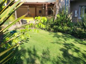 a yard with green grass and a house at The Lion's Den in George +4 photos