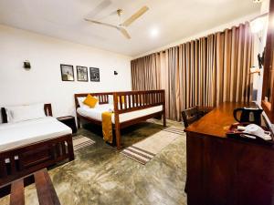 a bedroom with a bed and a desk with a telephone at New Moonstone Tangalle in Tangalle