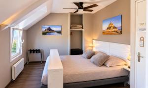a bedroom with a bed with a ceiling fan at Aux Chambres du Mont in Huisnes-sur-Mer