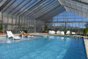 a woman laying on chairs next to a swimming pool at Grateus Apart in Villa General Belgrano