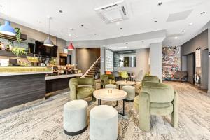 a lobby with green chairs and tables and a bar at Heeton Concept Hotel - Kensington London in London