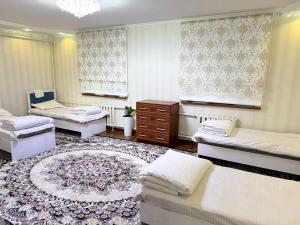 a living room with two beds and a rug at Hostel Hanysha in Kazarman