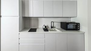 a kitchen with white cabinets and a black microwave at LA PIETRA Residence in Trani