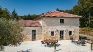 a stone house with a table and chairs in front of it at La Châtellerie du Gagnon in Champagnolles