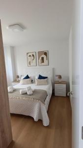 a white bedroom with a large bed with blue pillows at Las gaviotas,playa,piscinayparking in Malpica +29 photos