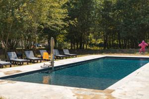 a swimming pool with chairs and a girl standing next to it at La Châtellerie du Gagnon in Champagnolles