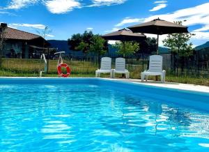 a swimming pool with three chairs and an umbrella at Casa Lueza in Alueza