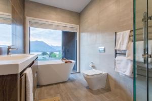 a bathroom with a tub and a toilet and a window at Grand Peninsula Lodge in Wanaka +52 photos