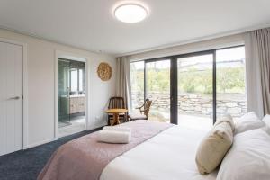 a bedroom with a large bed with a large window at Grand Peninsula Lodge in Wanaka