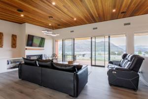 a living room with two couches and a tv at Grand Peninsula Lodge in Wanaka