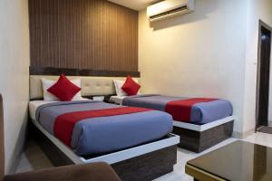two beds in a hotel room with red and blue at Abis Inn -Ballygunge in Kolkata