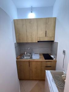 a small kitchen with wooden cabinets and a sink at GREISON Vacation House in Vlorë +26 photos