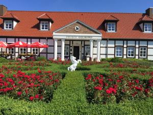 um cão branco sentado em frente a um edifício com flores em Dworek Golikowo em Sławno