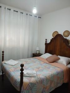 a bedroom with a large bed with a wooden headboard at Kannon 1 5-minute walk to all transport options at the Pragal terminal in Caparica