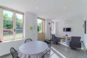 a living room with a table and chairs and windows at La Demeure des Sources - Iris - Avec climatisation in Bourbon-Lancy