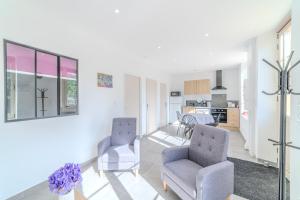 a living room with two chairs and a kitchen at La Demeure des Sources - Iris - Avec climatisation in Bourbon-Lancy