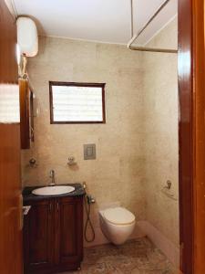 a bathroom with a toilet and a sink and a window at Siolim Serenity in Siolim