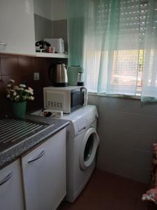 a kitchen with a washing machine and a microwave at Kannon 1 5-minute walk to all transport options at the Pragal terminal in Caparica